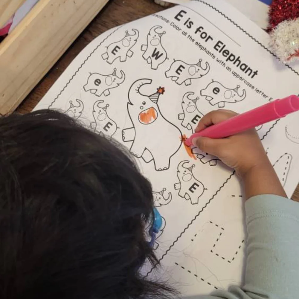 Child coloring an animal worksheet with pink marker